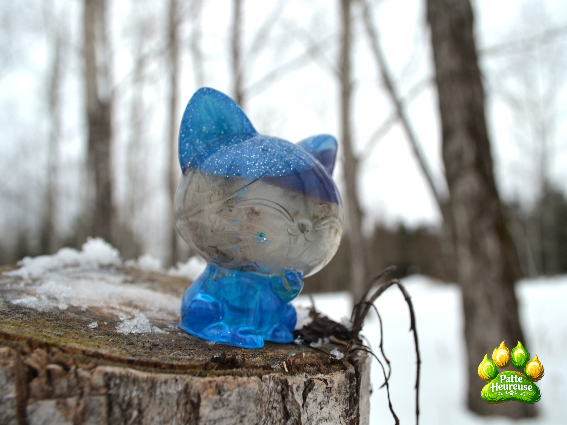 petit chat bleu translucide avec paillette ,vue de profil dans une foret enneigé